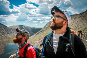 A picture of men in a mountainous area facing the sun; where they could use sunscreen.